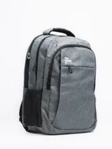 Mochila gris con cierre superior y bolsillo frontal con cierre. Tiene dos bolsillos laterales de red y logo de la marca en blanco en la parte superior.