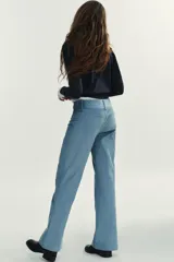 Pantalón de tiro alto con corte flare, confeccionado en pana. Presenta cintura ancha con trabillas, falsos bolsillos delanteros y cierre frontal con cremallera, botón oculto y ganchos metálicos.