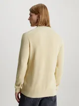 Sweater color crema de algodón con textura de canalé, cuello redondo e insignia de Calvin Klein Jeans bordada en el pecho.