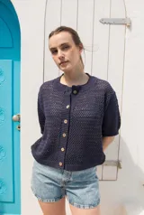 Saco tejido de punto calado con mangas al codo, cuello redondo y cierre frontal con botones de coco. Presenta un diseño versátil y ligero.