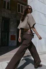 Chaqueta corta de punto color beige, con cuello redondo y manga tres cuartos. Cierre frontal con tres botones forrados a tono.