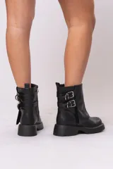Botas biker cortas de cuero sintético negro, con suela track, cierre lateral con cremallera y doble hebilla decorativa.