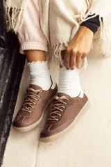 Zapatillas acordonadas de cuero color marrón chocolate, con detalle en blanco en el talón y suela color caramelo.