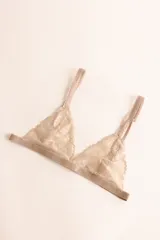 Soutien tipo bralette color beige, con copas triangulares de encaje floral y breteles finos con detalle de encaje.