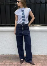 Jean 2 en 1 de color azul oscuro, con corte wide leg transformable a babucha mediante ajuste en los tobillos, tiro alto con cierre frontal de múltiples botones metálicos y bolsillos delanteros destacados.