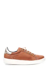 Deportivo de cuero liso color caramelo, con cordones beige y suela blanca. Presenta un detalle metalizado plateado en el talón.