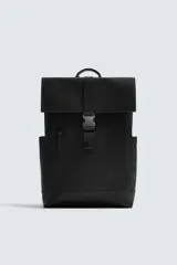 Mochila negra con acabado engomado, solapa con hebilla de liberación rápida, compartimento principal con espacio para dispositivos de hasta 13 pulgadas y bolsillo con cremallera, bolsillo frontal con cremallera, parte posterior acolchada con banda de sujeción para equipaje, asa de mano y dos asas de hombro ajustables y acolchadas.