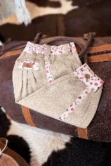 Bombacha de campo color beige, con detalles de tela estampada floreada en la cintura, bolsillos y botamangas. Cuenta con cintura elastizada y cierre con botón.