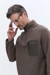 Buzo de polar color marrón con cuello alto y cierre frontal parcial. Presenta un bolsillo frontal con cierre en contraste de color y mangas largas.