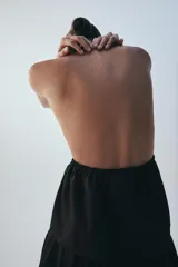 Top negro de cuello halter y escote en V pronunciado, confeccionado en popelina con frunces ajustables mediante cordón en el pecho y cierre frontal con lazada.