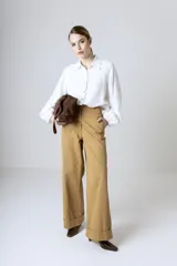 Camisa blanca de manga larga holgada, con cuello camisero, cierre frontal de botones y puños fruncidos con elástico.