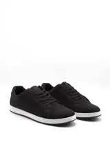 Zapatilla urbana de caña baja, color blanco, con cordones blancos. Presenta paneles laterales con perforaciones y un detalle de refuerzo en el talón de color negro.