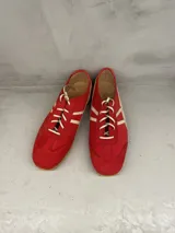Championes de cuero color rojo con detalles en blanco, diseño de perfil bajo, suela flexible y cierre con cordones.