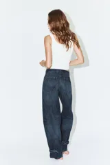 Jeans de tiro medio con diseño tipo balloon, cinco bolsillos y bajo ajustable con trabilla y botones. Cierre frontal con cremallera y botón metálico.