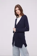 Saco tipo cárdigan de punto, color azul marino, con escote en V, mangas largas y bolsillos frontales aplicados. Presenta un diseño de corte recto con aberturas laterales en el ruedo.