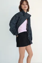 Falda pantalón de tiro medio confeccionada en tejido denim azul con costuras verticales decorativas, bolsillos delanteros y cierre frontal con cremallera y botón metálico.