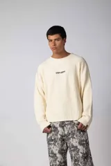Sweater de punto acanalado color marrón, con cuello redondo, mangas largas y calce relajado. Presenta una estampa pequeña en el centro del pecho.