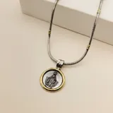 Collar con cadena de eslabones tipo serpiente en plata con detalles en oro, que sostiene un dije circular con la imagen de la Virgen Milagrosa en plata enmarcada en un borde de oro.
