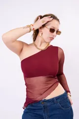 Remera asimétrica de un solo hombro color bordó, con cuerpo opaco y paneles de malla transparente en la cintura y en la manga larga.