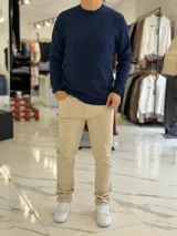 Buzo de hilo color beige claro, con cuello redondo y diseño clásico de manga larga.