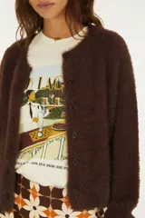 Cardigan básico de punto color marfil, con textura suave y esponjosa, cierre frontal de botones y mangas largas holgadas.