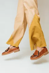 Mocasines de cuero color marrón con detalle de flecos y costuras en contraste en la parte delantera.