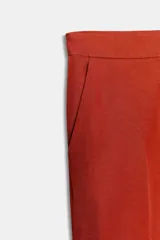 Pantalón de tiro alto color terracota, de tela satinada con textura sutil, corte de pierna ancha y bolsillos delanteros.
