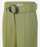 Pantalón pantalona color verde oliva, confeccionado en tejido orly con viscosa certificada. Presenta trabillas largas en la cintura, cierre tradicional, bolsillos y frisos delanteros. Incluye cinturón largo de tejido con hebilla irregular.
