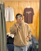 Buzo de pana color beige con cuello polo, cierre frontal parcial y forro interior de corderito. Presenta diseño oversized, bolsillos laterales y puños elásticos.
