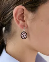 Dije colgante para aro con forma ovalada, borde metálico cobrizo y centro de resina con estampado de estrella blanca sobre fondo lila y amarillo.