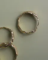 Brazalete rígido de diseño orgánico con textura irregular y acabado brillante, elaborado artesanalmente en metales nobles.