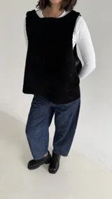 Chaleco de corte oversize confeccionado en material tipo corderito negro, con escote redondo y hebillas ajustables en los laterales.