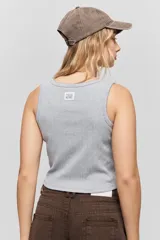 Musculosa de calce ajustado confeccionada en tejido acanalado, con escote redondo y detalle de puntilla en el escote y las sisas.