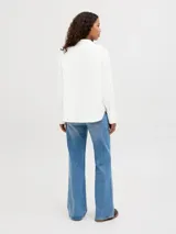 Camisa de popelín blanca de manga larga con cuello clásico y cierre frontal de botones ocultos, de ajuste relajado y puños anchos.