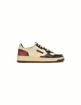 Championes de estilo retro inspirados en el tenis de los años 80, con acabado desgastado y efecto quemado. Presentan una combinación de cuero en tonos crema, negro y burdeos, con suela de goma envejecida y logo lateral característico de la marca.