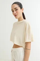 Remera color beige de corte cropped y mangas cortas.