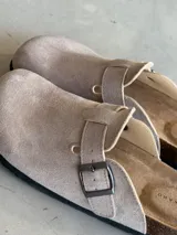 Zuecos color beige con hebilla metálica ajustable, plantilla anatómica de corcho y suela de goma.