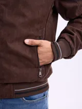 Campera reversible de gamuza sintética color marrón, con cierre frontal, cuello alto y puños de tejido acanalado con detalles de rayas.