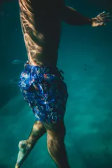 Short de baño azul con estampado floral y geométrico, cuenta con cintura elástica, dos bolsillos laterales y un bolsillo trasero.