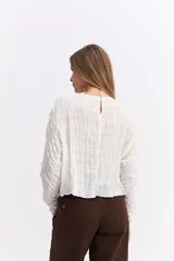 Blusa de manga larga con textura fruncida en toda la prenda, cuello redondo y corte relajado.