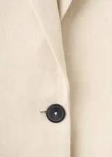 Blazer Paola de corte recto, color beige, confeccionado en mezcla de lana y lino. Presenta cuello pico con solapa, mangas largas, un bolsillo de ribete en el pecho, dos bolsillos con solapa en los laterales y cierre frontal de un botón oscuro.