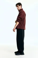 Buzo deportivo de polar color bordó, con cuello alto y cierre frontal parcial. Presenta mangas largas de corte caído y bolsillos laterales integrados en la costura.