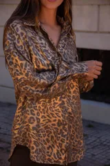 Camisa de corte clásico con cuello camisero, mangas largas con puños abotonados y cierre frontal con botones. Presenta un estampado animal print con acabado satinado y una caída fluida.