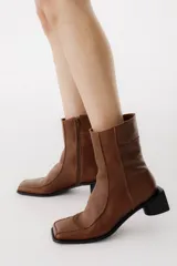 Bota corta de cuero color bordó, con punta cuadrada y taco bloque bajo. Cierre lateral con cremallera.