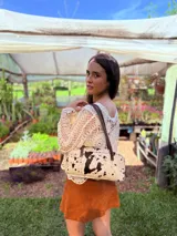 Cartera baguette de cuero color crudo con manchas negras, forro interno de tela y correa de cuero marrón.