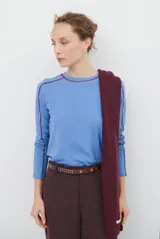 Remera de manga larga color azul, con costuras a la vista en color bordó que resaltan el diseño de las mangas raglán.