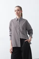 Camisa a rayas verticales blancas y marrones, de manga larga con puños abotonados, cuello camisero y botones frontales. Incluye un bolsillo en el pecho con bordado sutil.