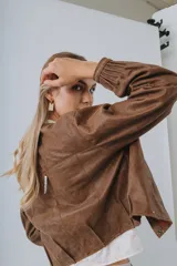 Campera bomber de cuero color marrón, con mangas abullonadas, puños elásticos y cierre frontal con botones a presión.