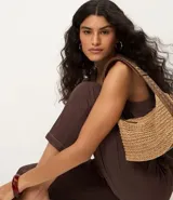 Blusa sin mangas color marrón, con escote redondo y corte recto. Presenta paneles laterales en tejido texturizado con rayas y una abertura vertical en la espalda con cierre discreto.