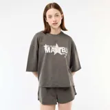 Remera oversize gris con efecto acid wash, cuello redondo, mangas cortas y estampa frontal con la palabra 'MALIBU' y estrellas en tonos blancos y rosados.